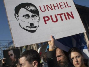 Woman holds a sign depicting Russian President Vladimir Putin as Adolf Hitler as she attends a rally at Independence Square in Kiev
