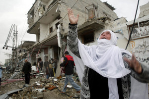 Palestinian woman shouts in front of houses in Rafah