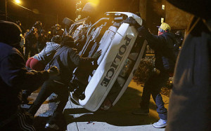 Protesters flip over a Ferguson police car in Ferguson