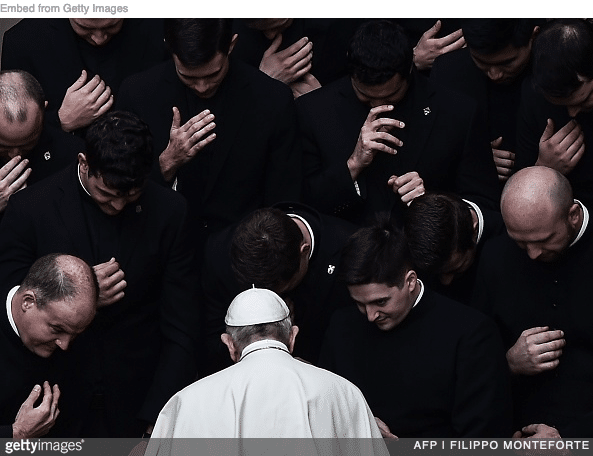 Pope Francis surrounding by priests
