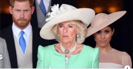 camilla standing in front of brooding harry and smirking meghan